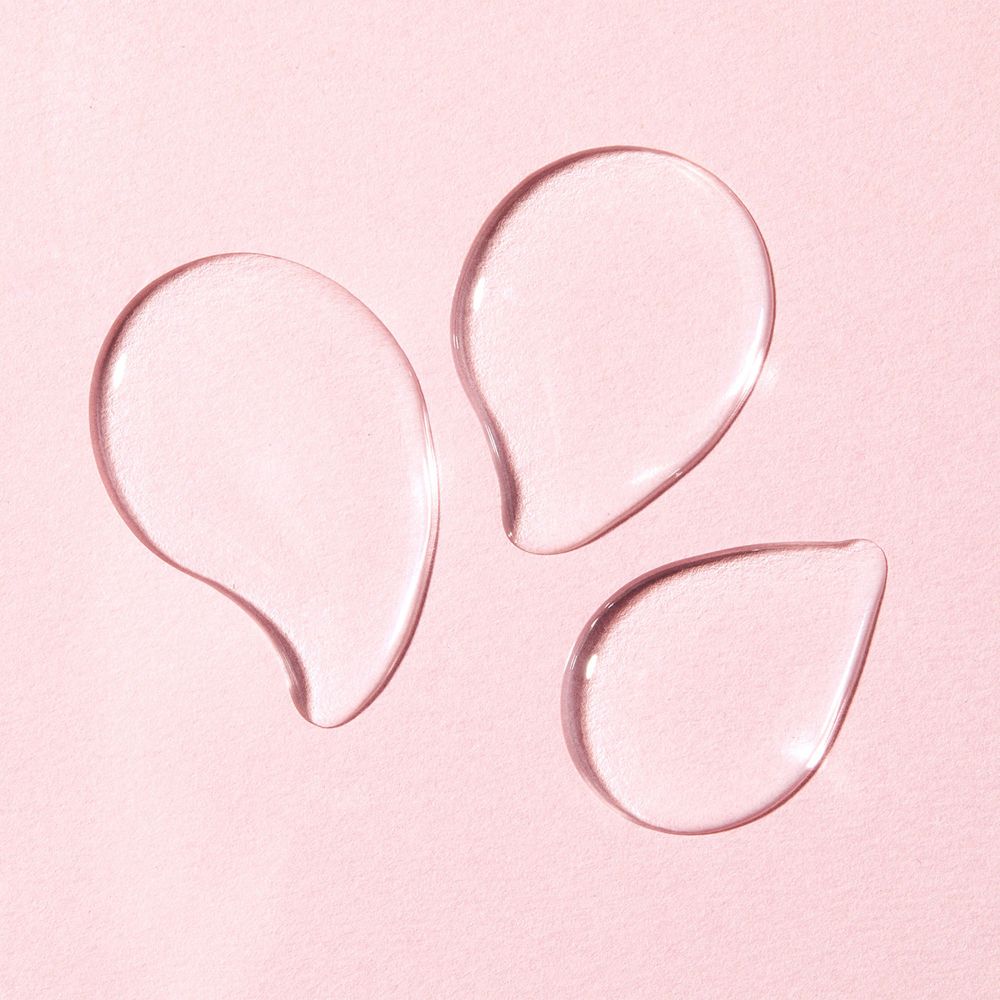 Tre gocce trasparenti su sfondo rosa. Nessuna scritta visibile.