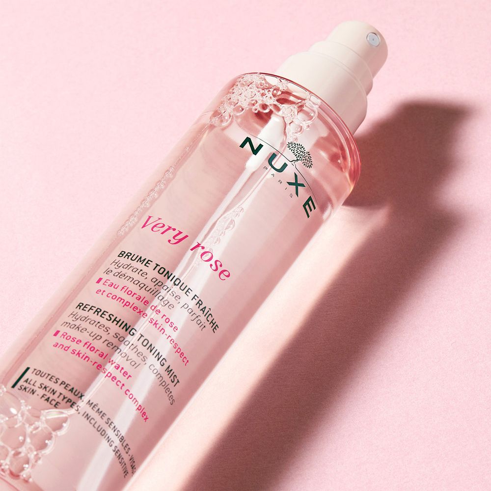 Flacone spray NUXE Very Rose in diagonale. Sfondo rosa. Logo e testo visibili.
