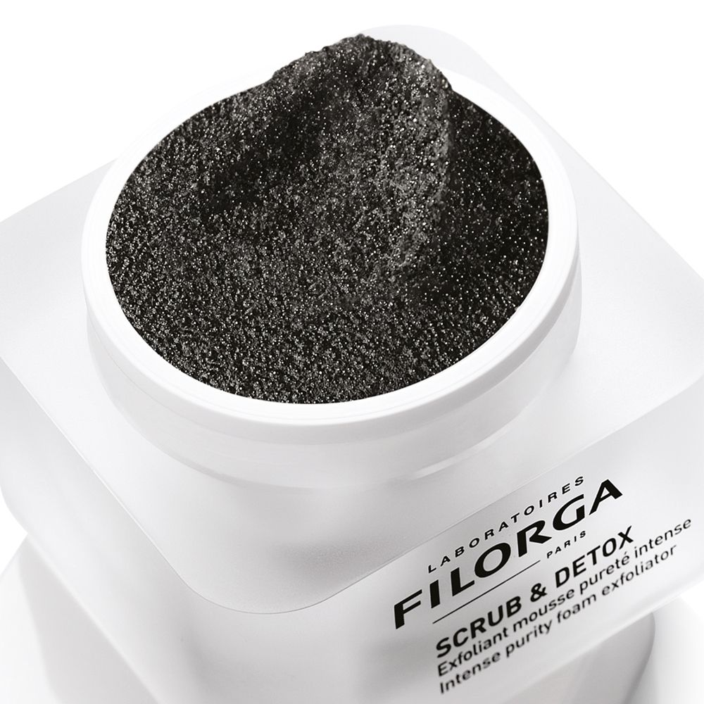 Gros plan d'un pot blanc avec contenu noir. Inscription FILORGA SCRUB & DETOX. Texte: Exfoliant mousse pureté intense, Intense purity foam exfoliator.
