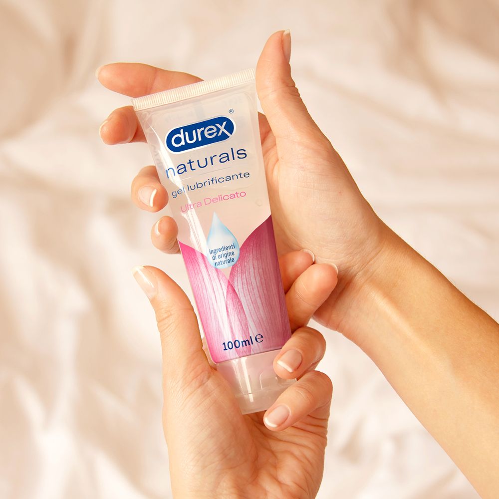 Hände halten eine transparente Tube Durex Naturals Gel. 100ml. Rosa Blütenmuster auf der Tube.