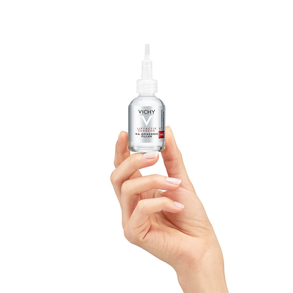 Hand hält eine kleine Glasflasche mit Serum. Aufschrift: VICHY LIFTACTIV SUPREME H.A. EPIDERMIC FILLER.