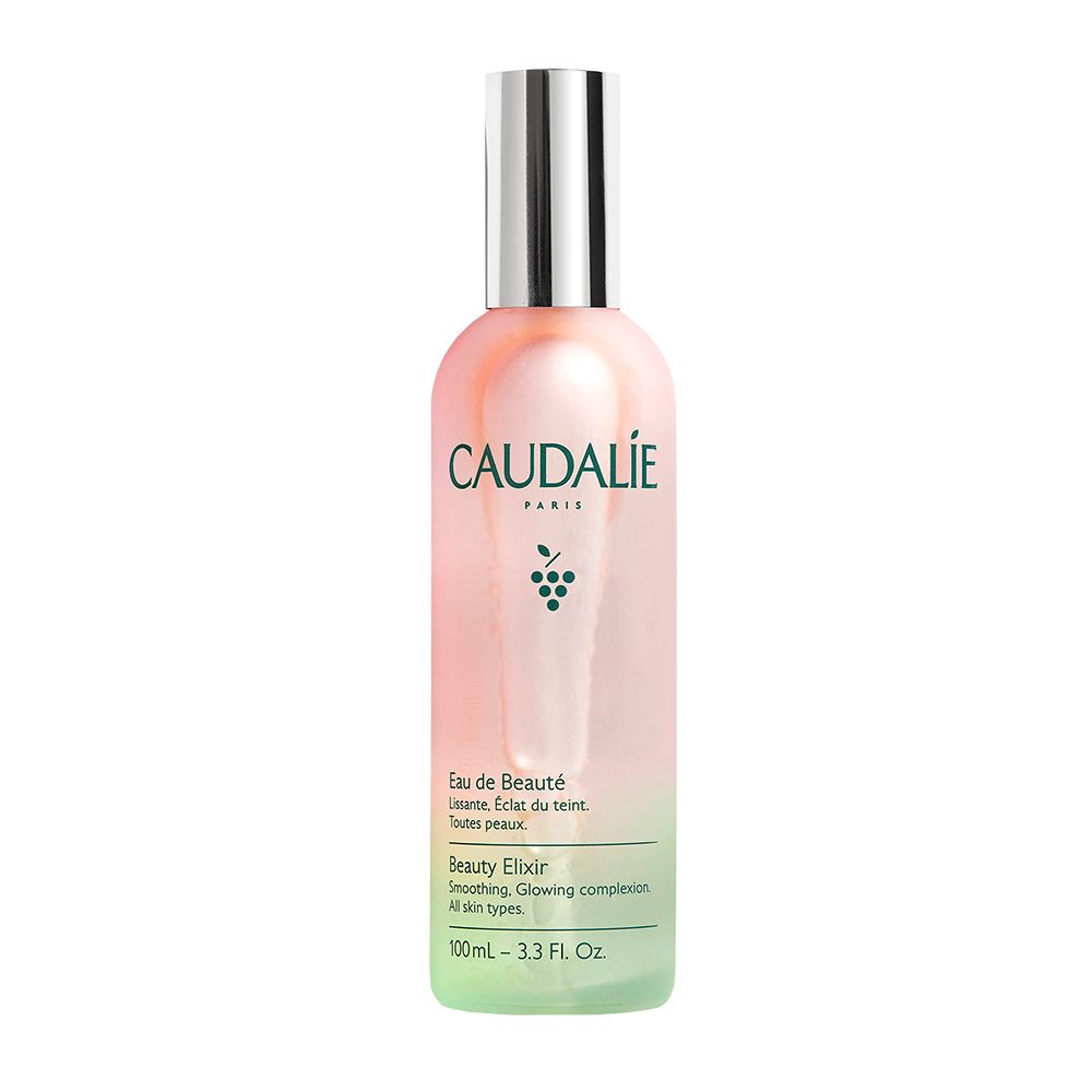 Flacone Caudalie Eau de Beauté con gocce d'acqua. Sfumatura rosa-verde, tappo argentato. Acino d'uva accanto.