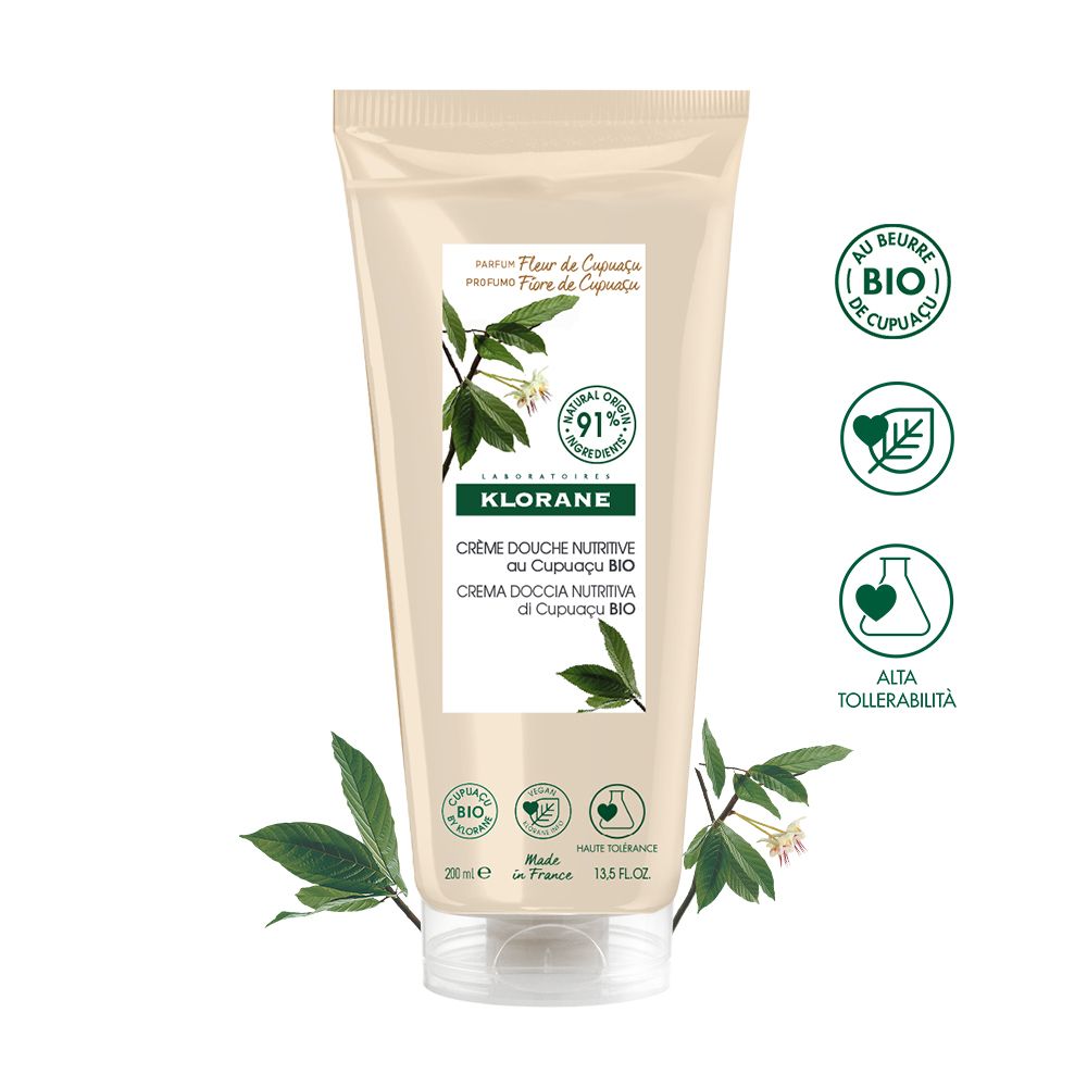 Beige Tube mit weißem Etikett. Klorane Crème Douche Nutritive au Cupuaçu BIO. Zusätzliche Symbole und Blätter.