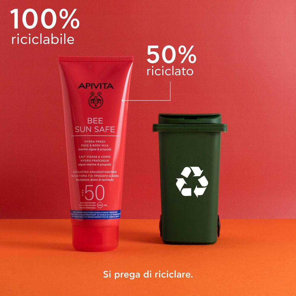 Tubo rosso APIVITA BEE SUN SAFE accanto a un bidone verde. Testo: 100% riciclabile, 50% riciclato.
