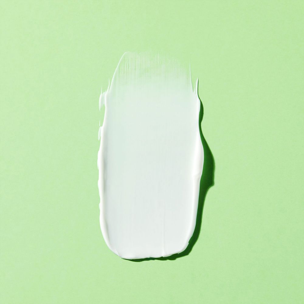 Macchia di crema bianca su sfondo verde. Nessuna scritta.