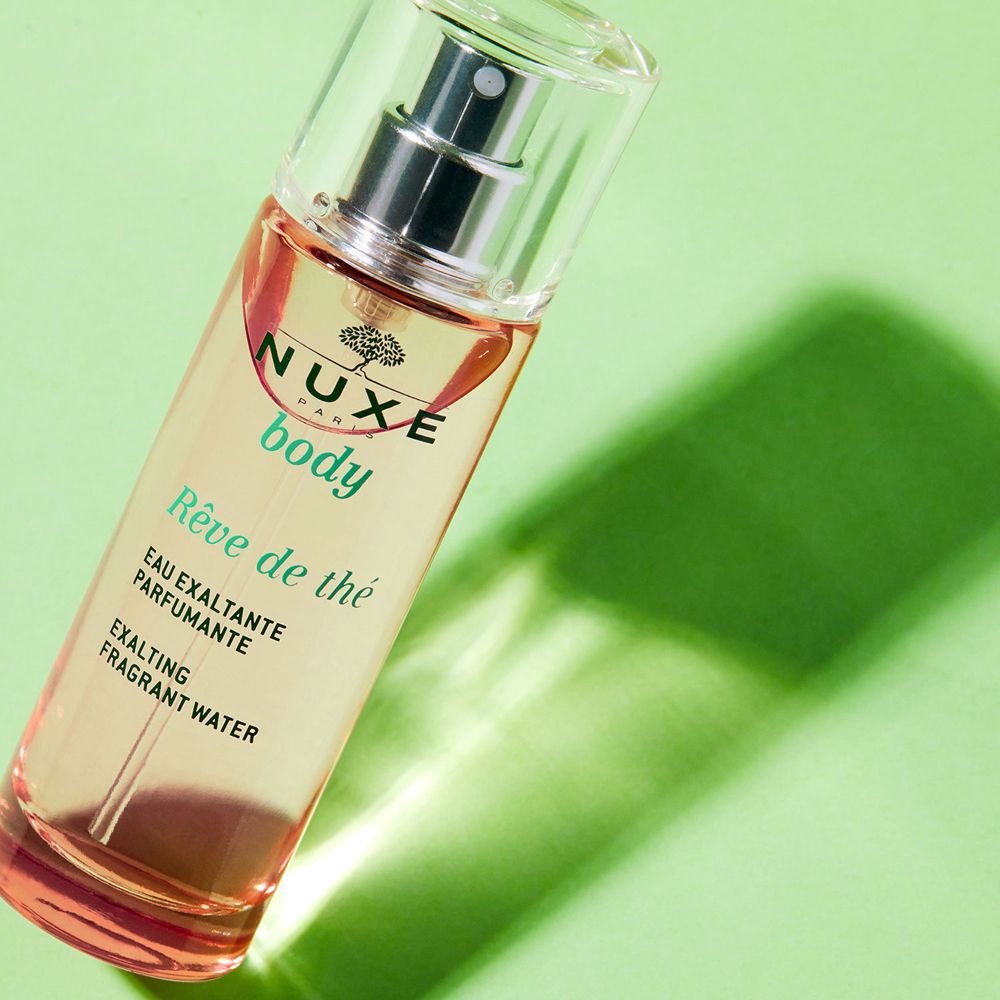Flacone inclinato con vaporizzatore. Scritte: Nuxe body, Rêve de thé, Eau exaltante parfumante, Exalting fragrant water.