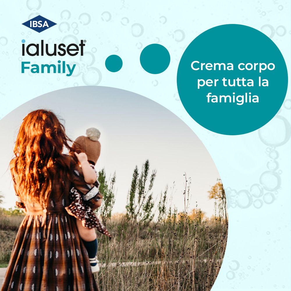 Donna tiene in braccio un bambino. Logo Ialuset Family. Testo: Crème corps per tutta la famiglia. Sfondo: campo.