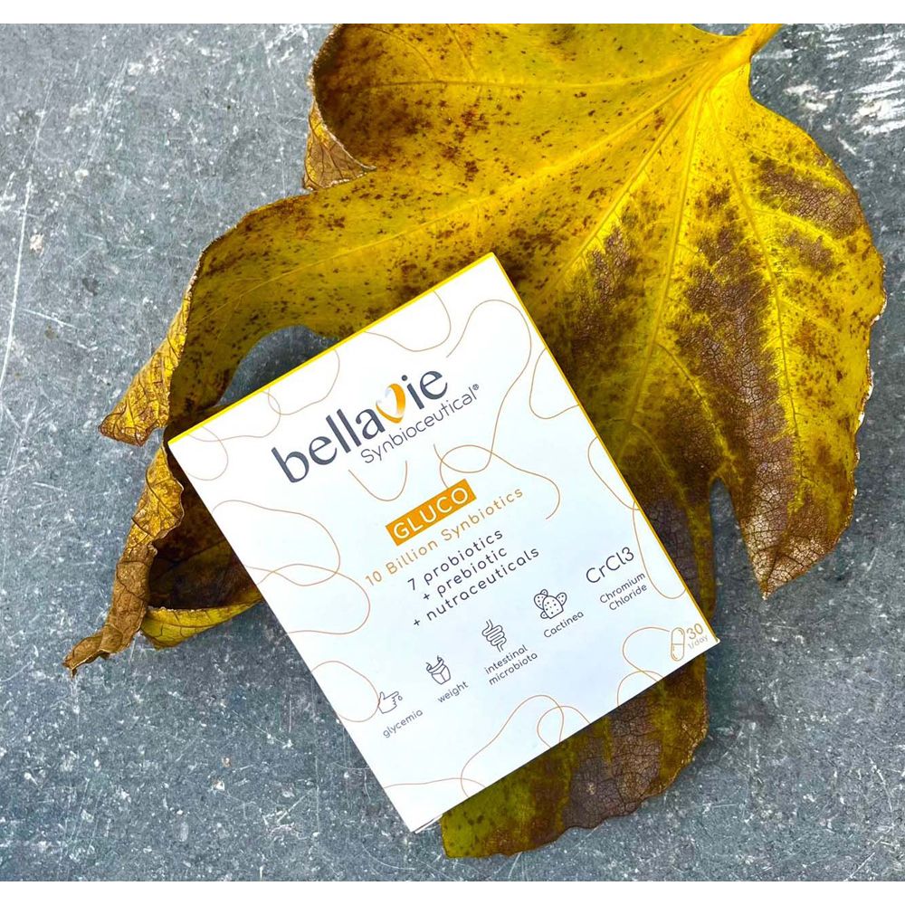 Doosje BellaVie GLUCO capsules. Opschrift: 10 miljard synbiotica, 7 probiotica, prebiotica, nutraceuticals. Op een geel blad.