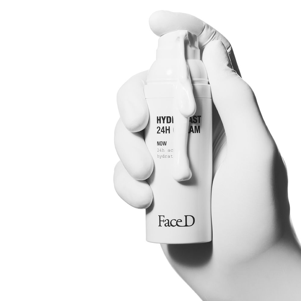 Hand mit weißem Handschuh hält eine weiße Creme-Tube. Aufschrift: HYDRAFAST 24H CREAM, Face D.