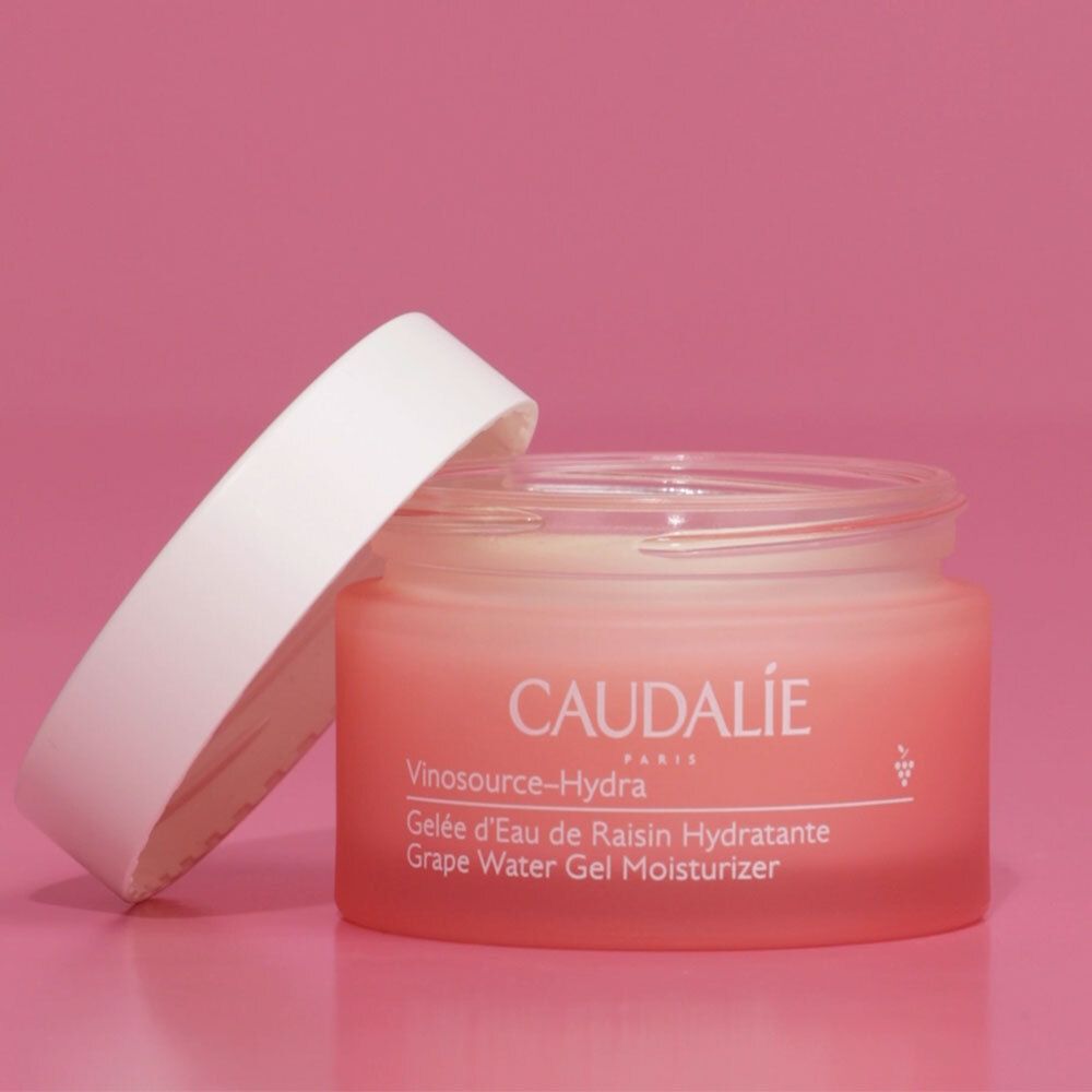 Vaso rosa con coperchio bianco aperto. Scritta: CAUDALIE, Vinosource-Hydra, Gelée d'Eau de Raisin Hydratante, Grape Water Gel Moisturizer.