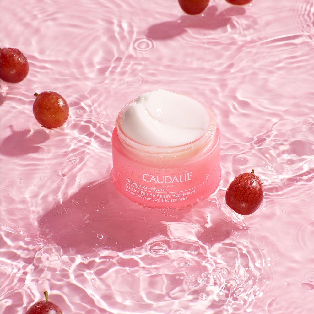 Vaso rosa con uva in acqua. Scritta: CAUDALIE, Vinosource-Hydra, Gelée d'Eau de Raisin Hydratante, Grape Water Gel Moisturizer.