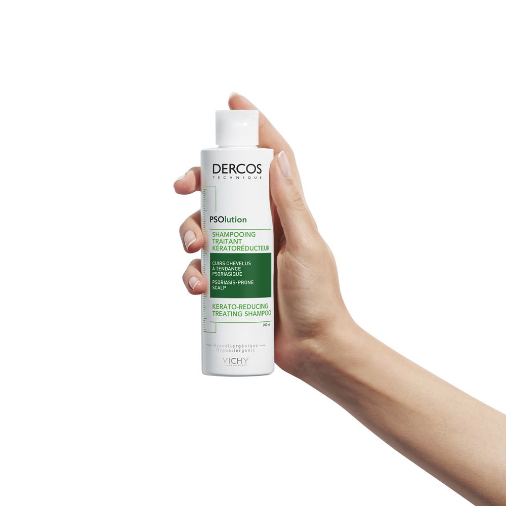 Mano che tiene il flacone di shampoo. Dercos PSolution. Per forfora e cuoio capelluto pruriginoso.
