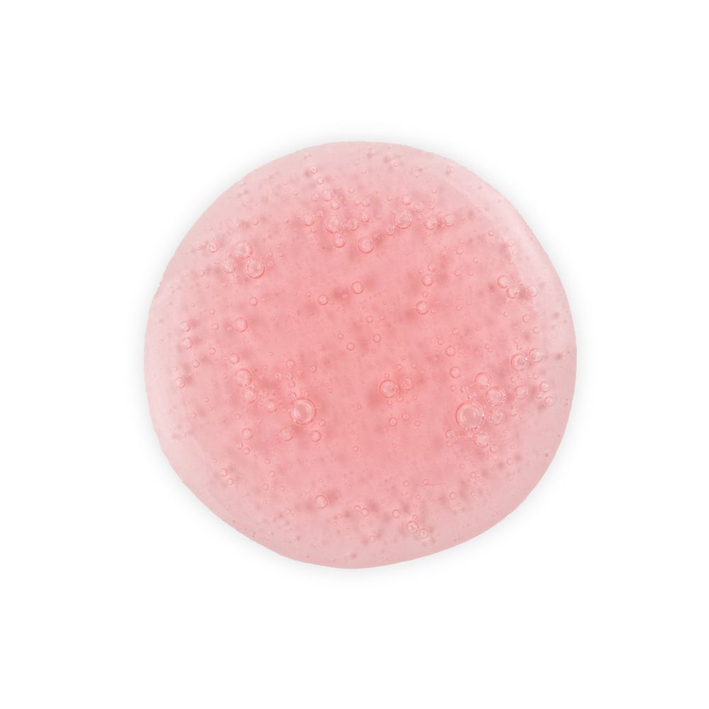Macchia rotonda di shampoo rosa. Bolle visibili. Sfondo bianco.