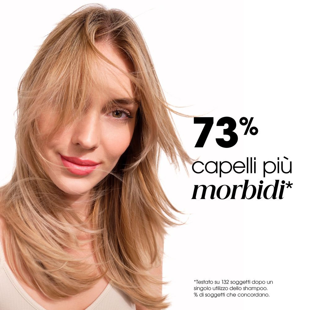 Donna bionda con capelli al vento. Testo: 73% capelli più morbidi.