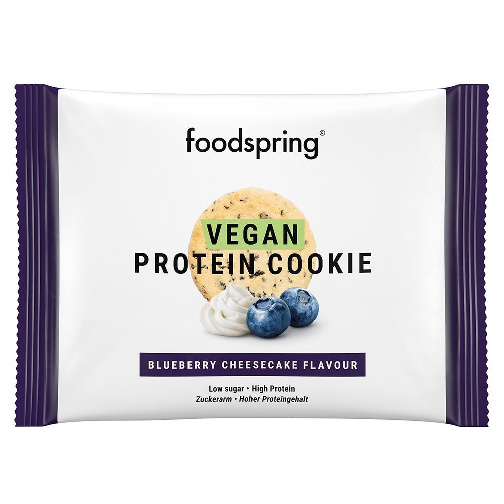 Confezione di Foodspring Vegan Protein Cookie. Scritta: Vegan Protein Cookie, gusto cheesecake ai mirtilli. Immagine: biscotto, mirtilli.