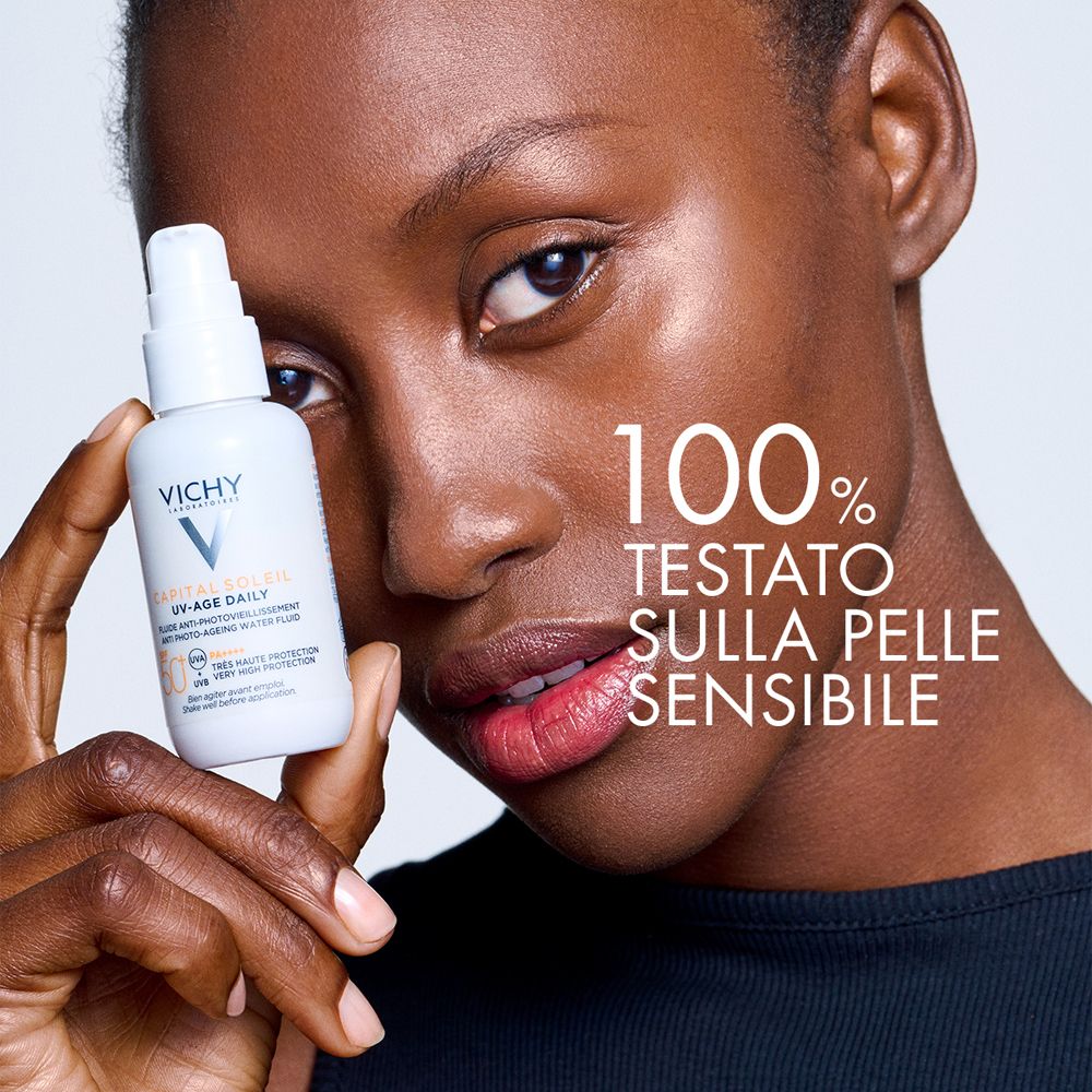 Flacone vicino al viso. Testo: 100% testato su pelle sensibile. Vichy Capital Soleil UV-Age Daily.