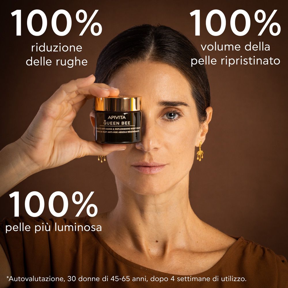 Donna tiene vaso davanti al viso. Testo: APIVITA QUEEN BEE, crema notte. 100% riduzione rughe, volume pelle.