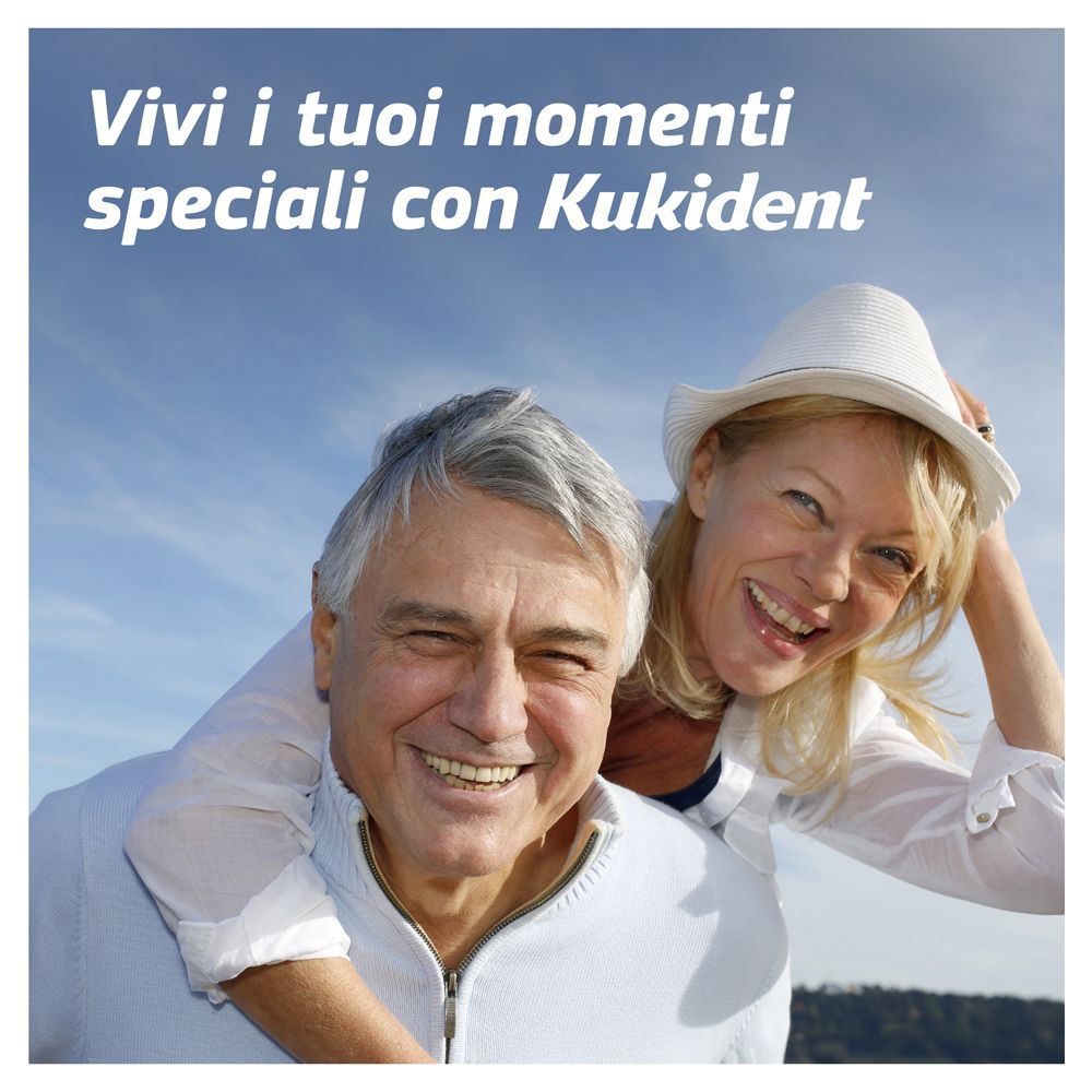 Coppia sorridente. Uomo che porta donna. Testo: Vivi i tuoi momenti speciali con Kukident.