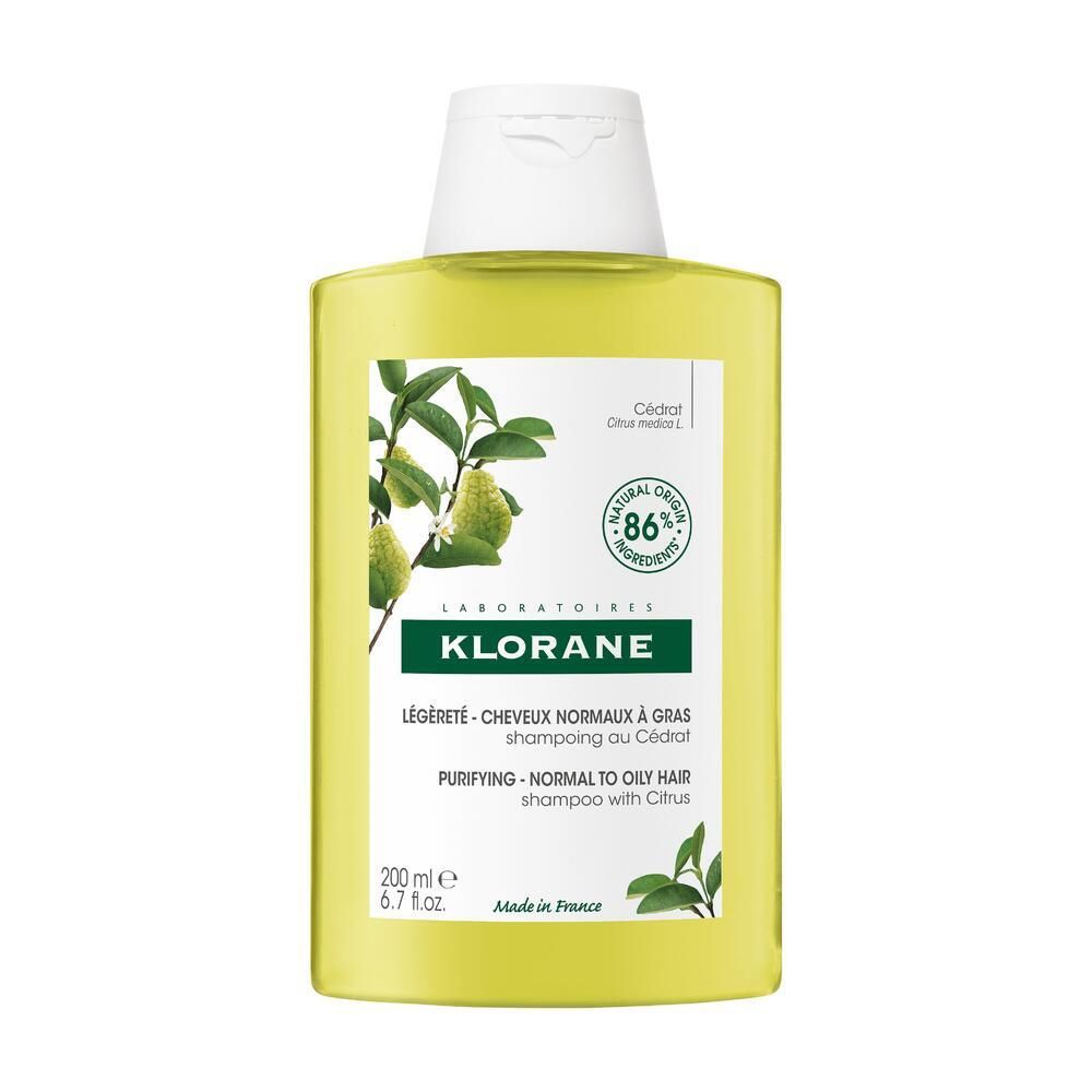 Flacone di shampoo Klorane giallo con tappo bianco. Etichetta con informazioni e illustrazione di cedro.