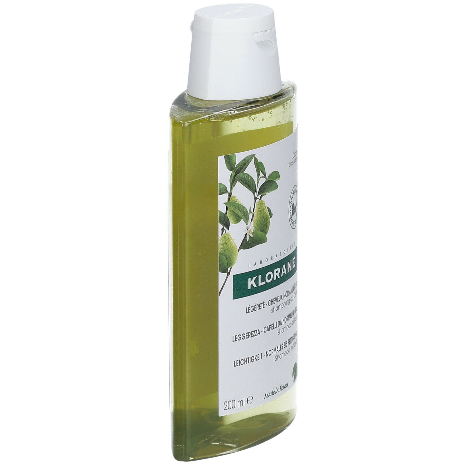 Flacone di shampoo Klorane inclinato. Liquido giallo, tappo bianco. Etichetta con nome e ingredienti.
