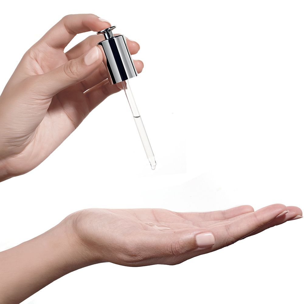 Mani che tengono una pipetta con liquido. Pipetta con tappo argentato. Liquido che gocciola nel palmo.