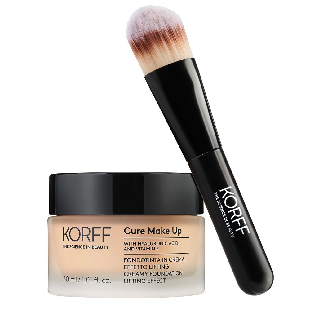 Fondotinta in crema KORFF Cure Make Up e pennello. Flacone in vetro beige, coperchio nero. Pennello con manico nero e setole chiare.