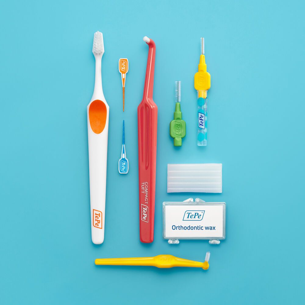 Set per l'igiene orale con spazzolino, scovolini, filo interdentale e cera su sfondo blu. Contiene prodotti TePe®.