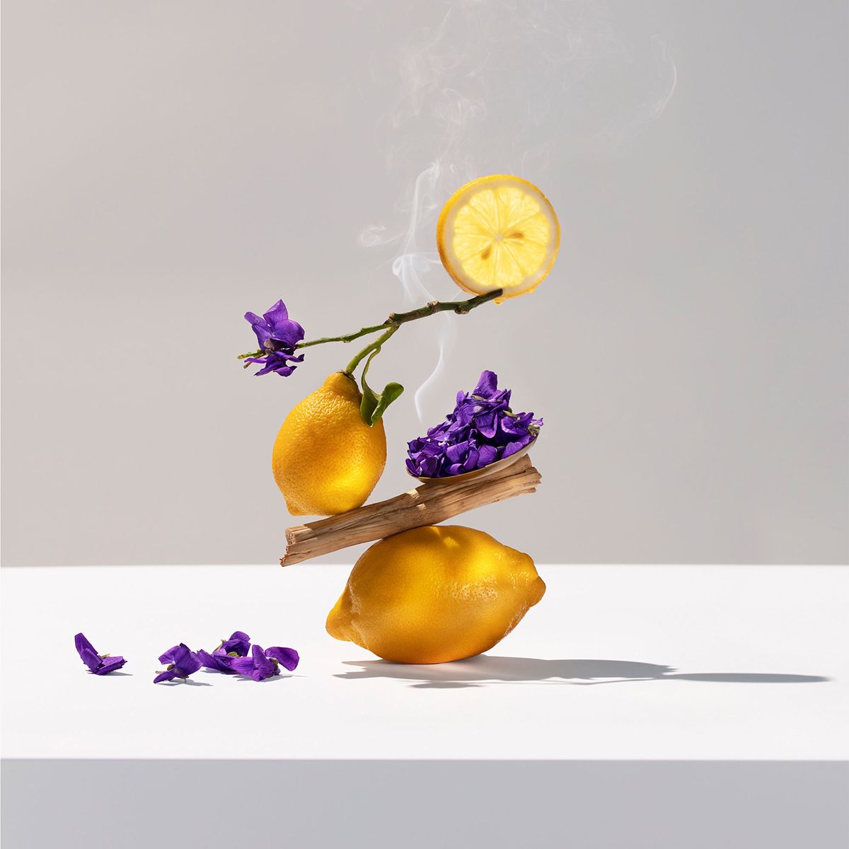 Limoni, fiori e pezzi di legno. Alcuni elementi fluttuano. Sfondo bianco.