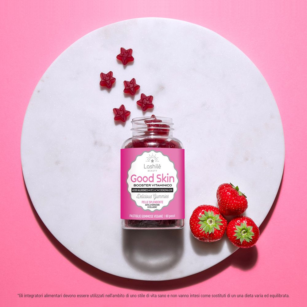 Flacone di prodotto con caramelle gommose e fragole su piatto bianco. Sfondo rosa. Testo: Good Skin, Delicious Gummies.