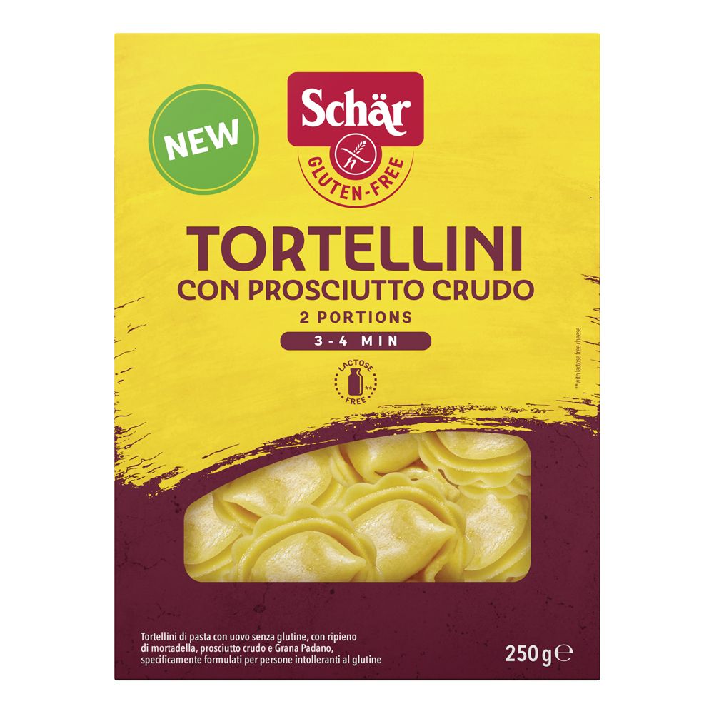 Scatola gialla di tortellini. Scritto: Schar, senza glutine, Tortellini con Prosciutto Crudo, 2 porzioni, 3-4 min. Finestra con tortellini.