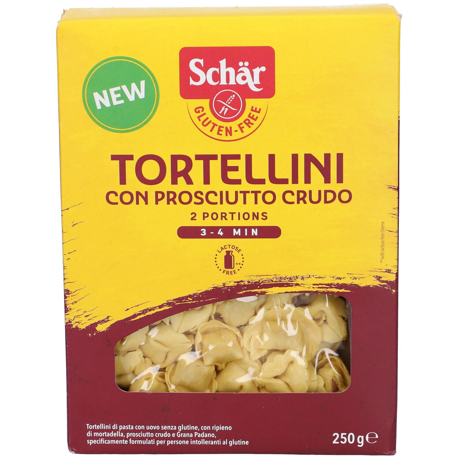 Scatola gialla di tortellini. Scritto: Schar, senza glutine, Tortellini con Prosciutto Crudo, 2 porzioni, 3-4 min. Finestra con tortellini.
