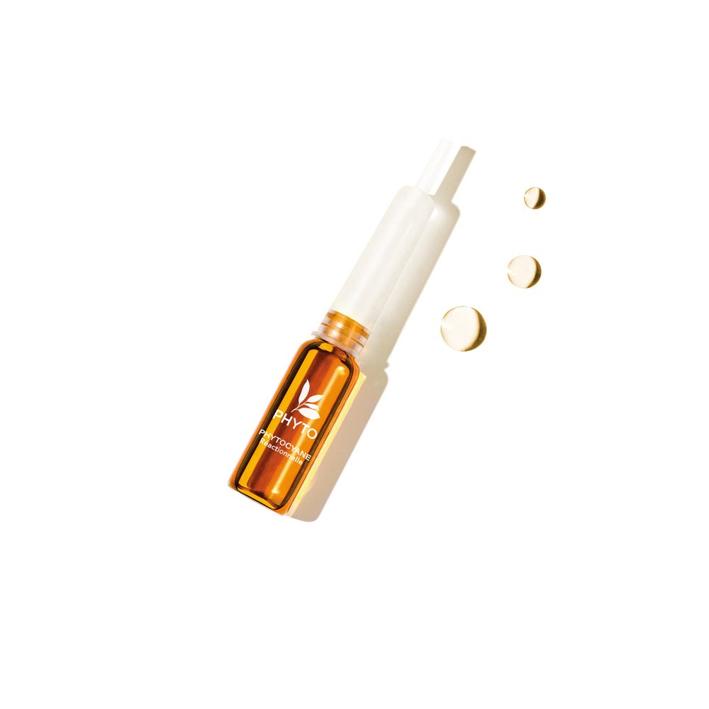 Fiala con contenuto giallo e applicatore bianco. Tre gocce gialle accanto. Su sfondo bianco.