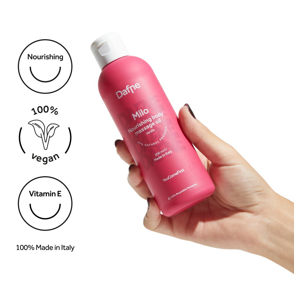 Mano che tiene flacone rosa con tappo bianco. Scritta: Dafne Milo, olio massaggio corpo Vaniglia. Vegan, Vitamina E.