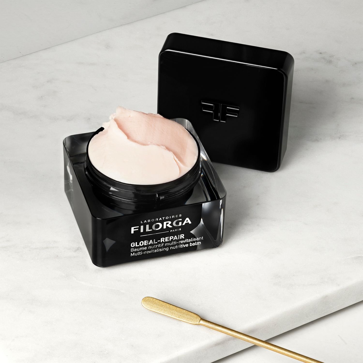 Vasetto aperto con crema, coperchio nero accanto. Spatola dorata. Scritta FILORGA GLOBAL-REPAIR.