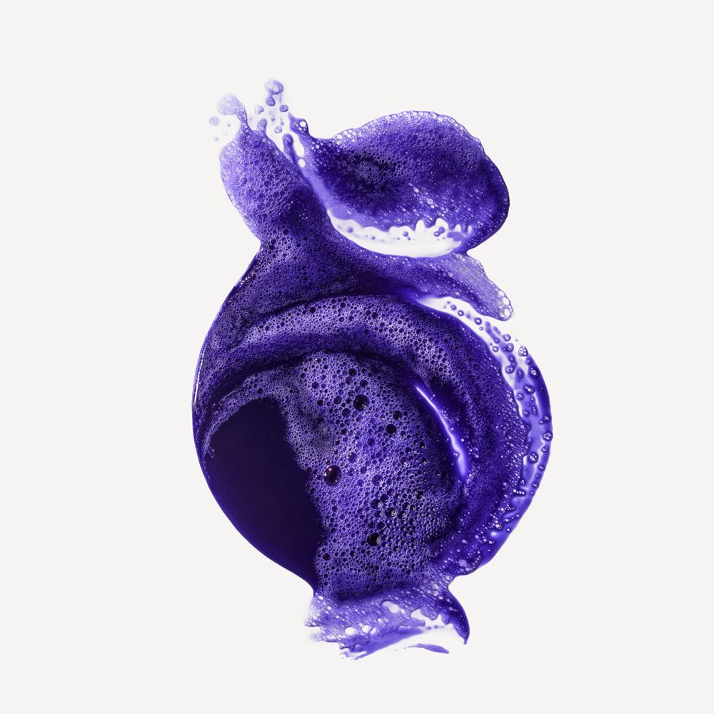 Künstlerische Darstellung von lila Shampoo-Schaum. Schaum mit Blasen, wellenförmig. Auf weißem Hintergrund.