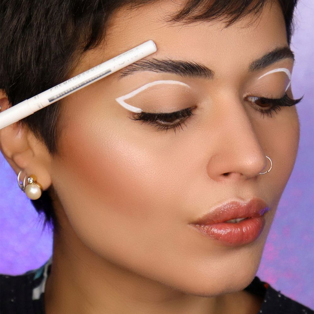 Primo piano di una donna che usa un eyeliner bianco. L'eyeliner viene applicato sulla palpebra.
