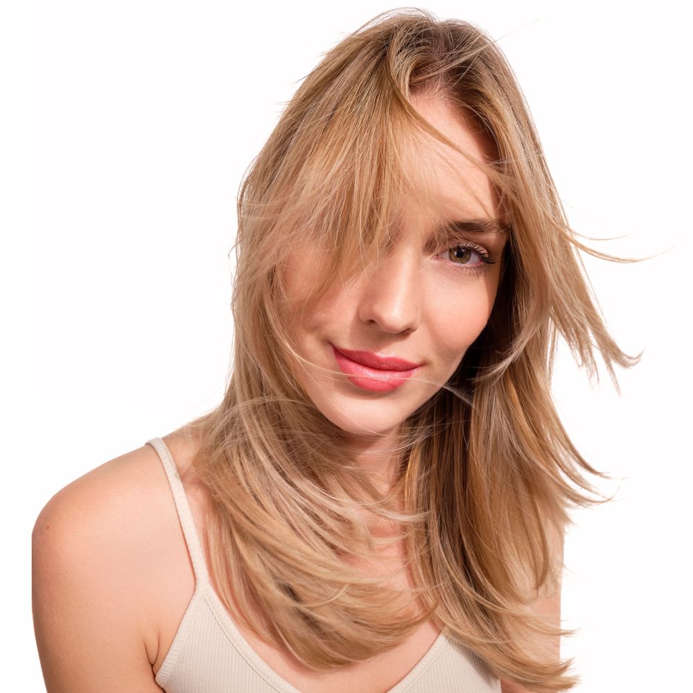 Porträt einer Frau mit blondem Haar. Sie trägt ein weißes Top.