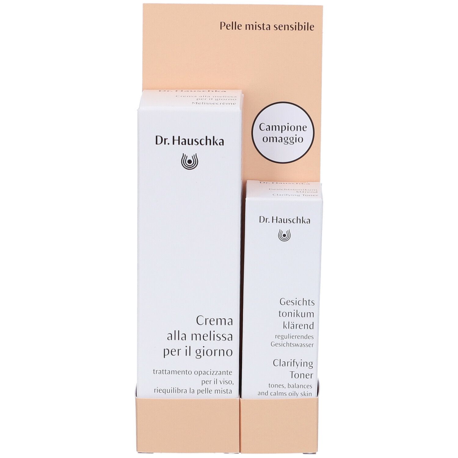 Due prodotti Dr. Hauschka in confezione bianca. Espositore con testo: Pelle mista sensibile e Campione omaggio.