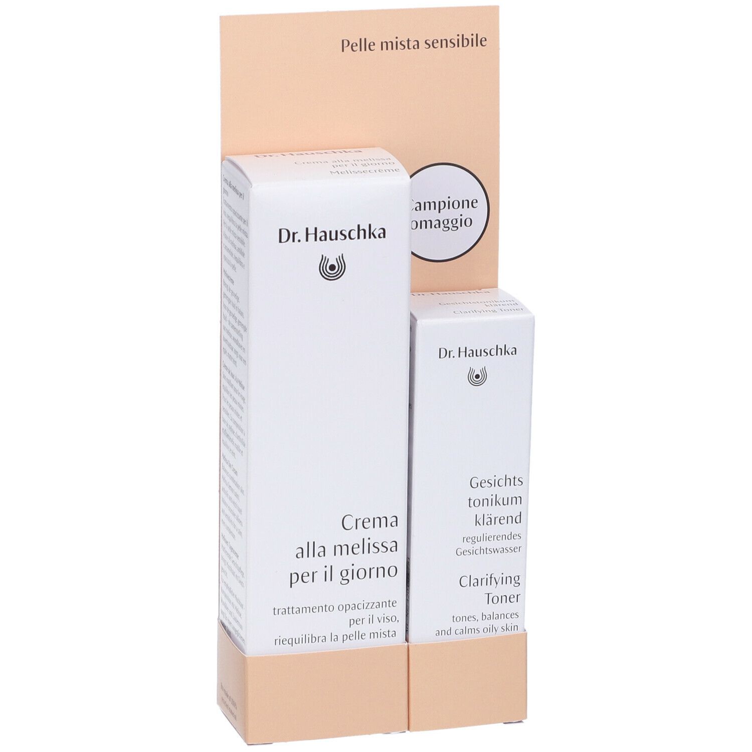 Due prodotti Dr. Hauschka in confezione bianca. Espositore con testo: Pelle mista sensibile e Campione omaggio.