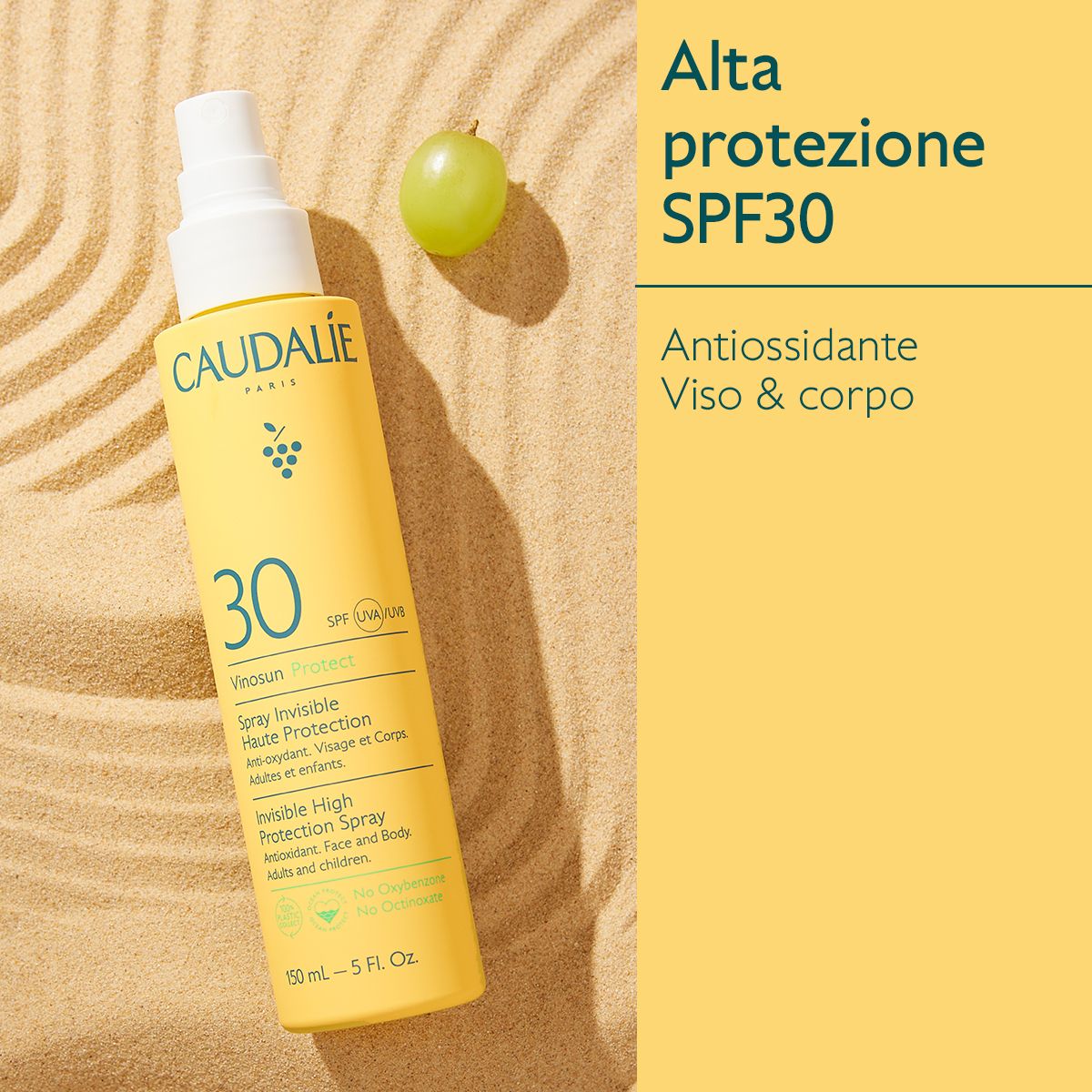 Flacone giallo con vaporizzatore. Caudalie Vinousun Protect 30. Spray solare. Posizionato sulla sabbia.