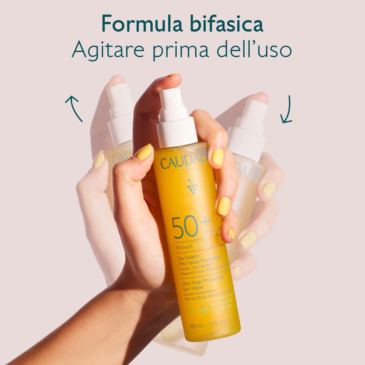 Mani che tengono spray solare. Liquido giallo. Scritte: Caudalie, 50+, Vinousun Protect. Testo: Formula bifasica, Agitare prima dell'uso.