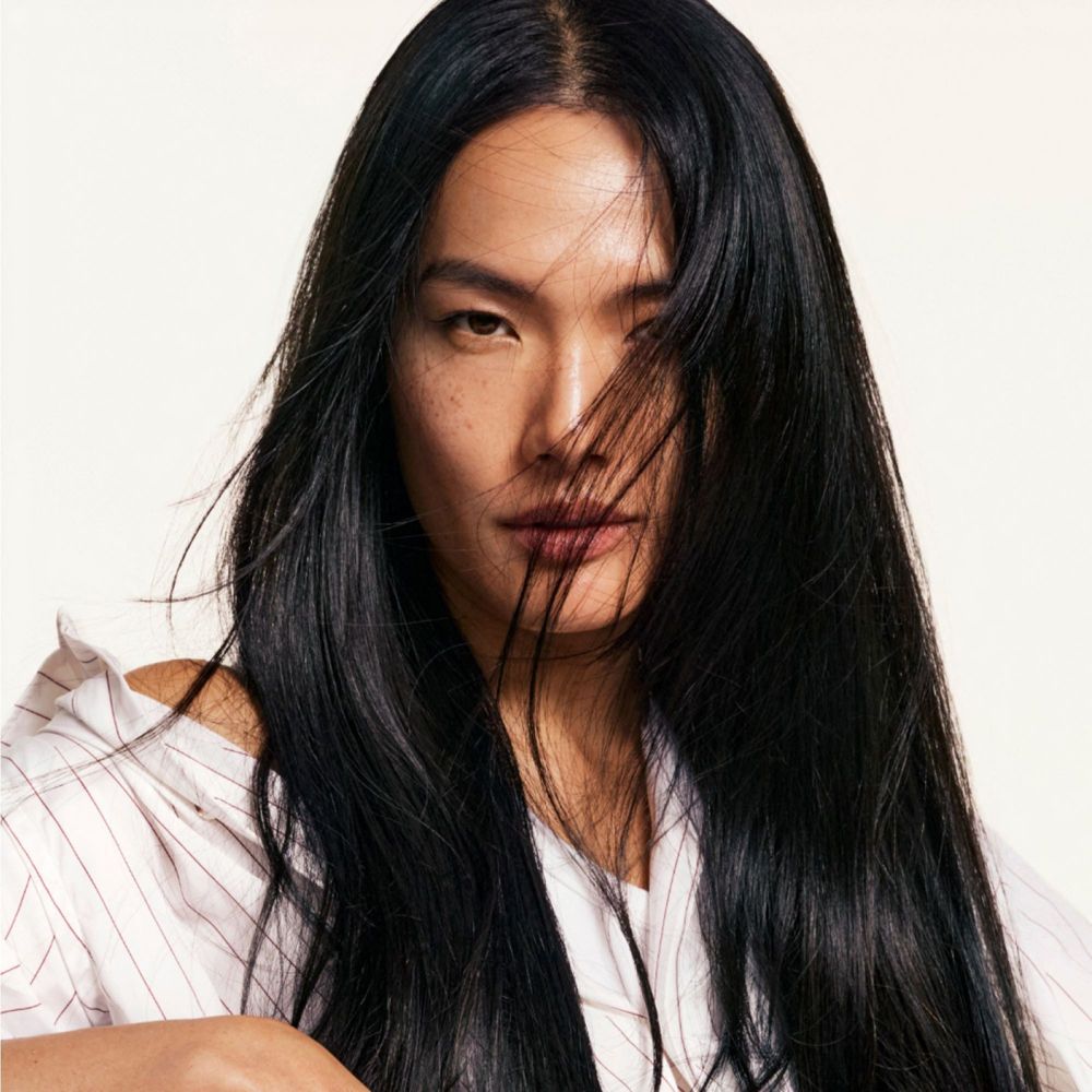 Porträt einer Frau mit langen, schwarzen Haaren. Sie blickt in die Kamera. Ihr Haar bedeckt teilweise ihr Gesicht.