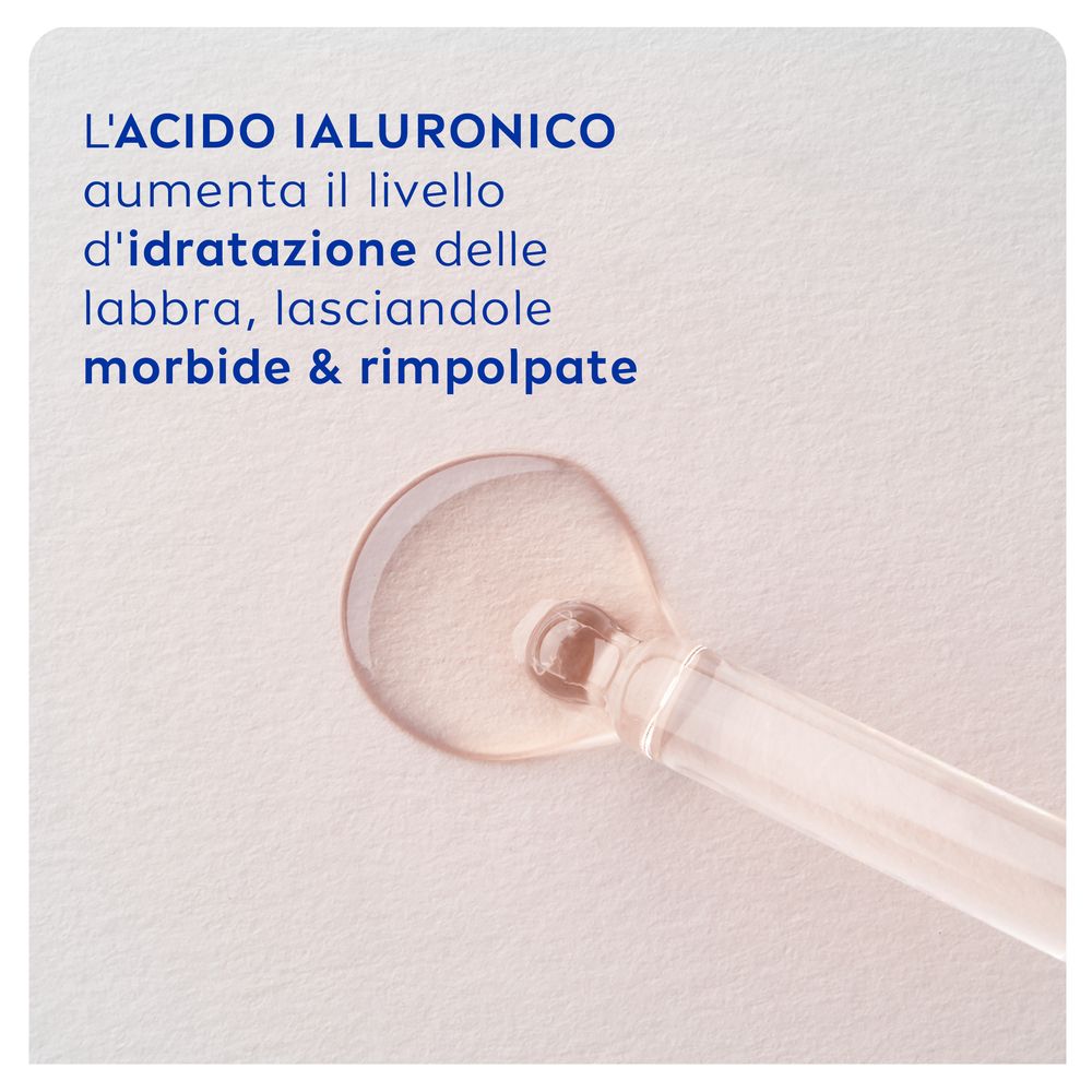 Primo piano di un liquido. Testo: 'L'ACIDO IALURONICO aumenta il livello d'idratazione delle labbra, lasciandole morbide & rimpolpate'.