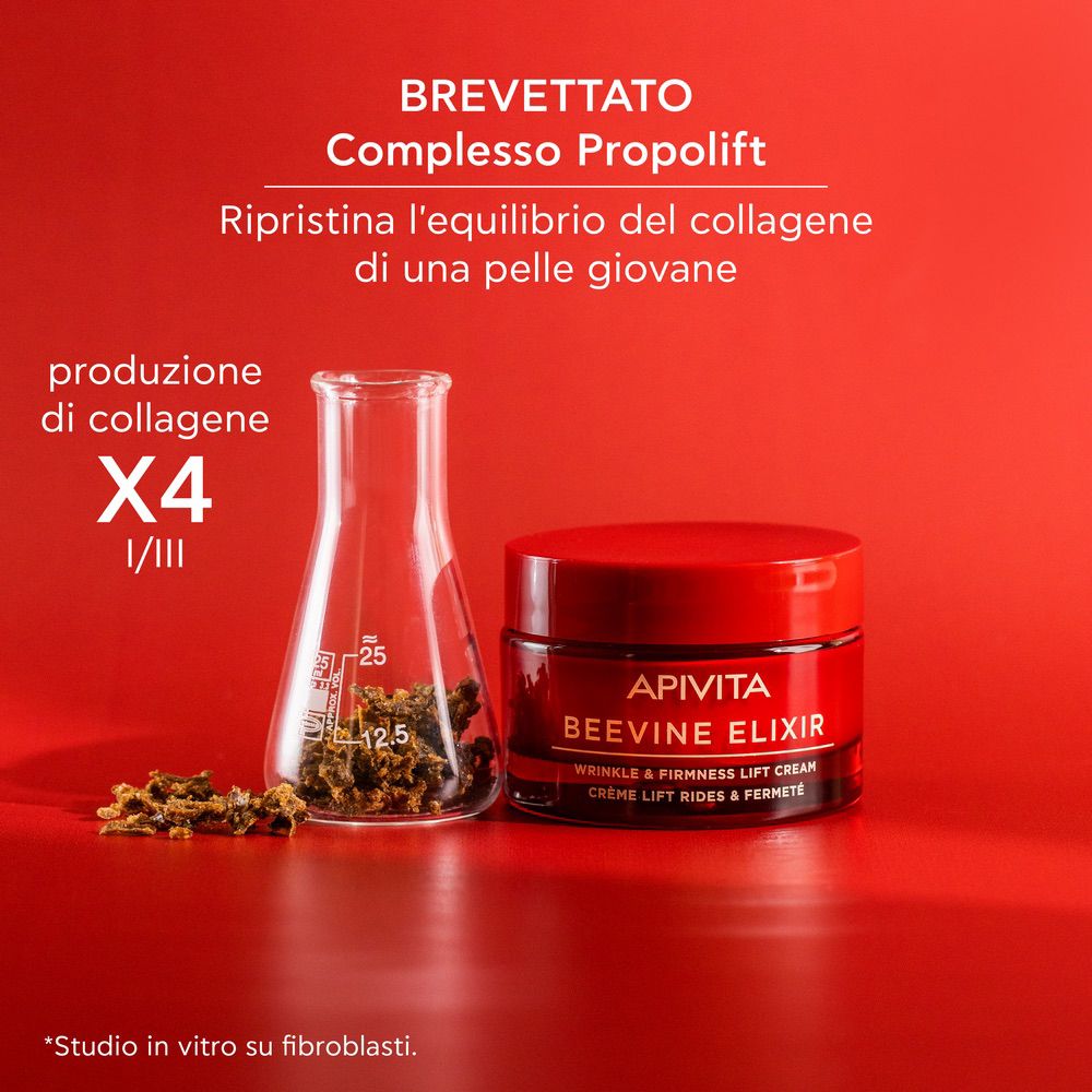 Vaso di crema rosso con vetro da laboratorio. Testo: APIVITA BEEVINE ELIXIR. Testo: WRINKLE & FIRMNESS LIFT CREAM. Crème lift rides & fermeté. X4 produzione di collagene.