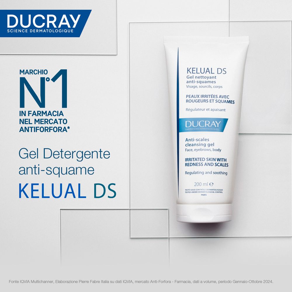 Pubblicità del prodotto con tubo bianco. Contiene "KELUAL DS" e "DUCRAY". Testo: "MARCHIO N.1" e "Gel Detergente anti-squame". Sfondo: blu-bianco.