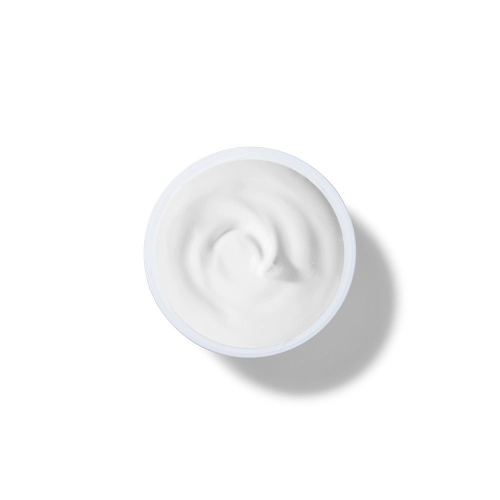 Vista dall'alto di una crema bianca in un vasetto bianco. Consistenza cremosa, a spirale.