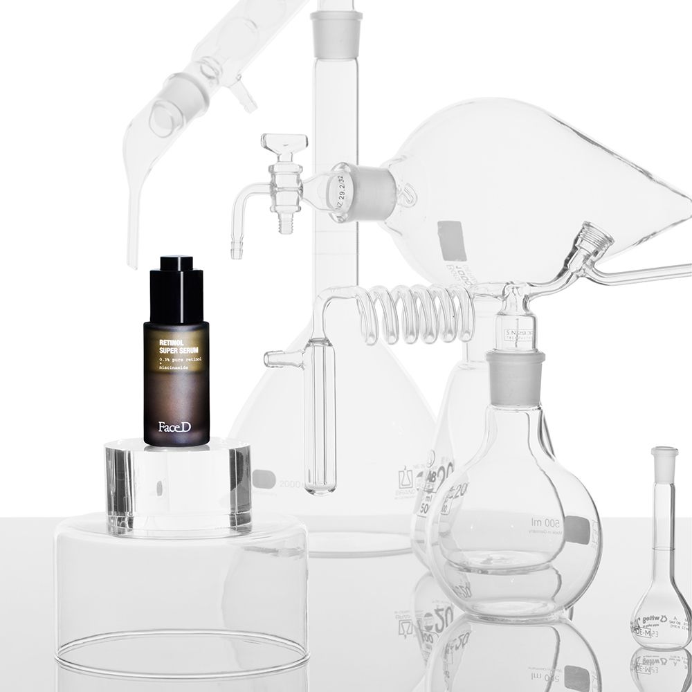 Braune Flasche mit schwarzem Verschluss auf Podest. Laborutensilien im Hintergrund. Aufschrift: Retinol Super Serum. Face D.