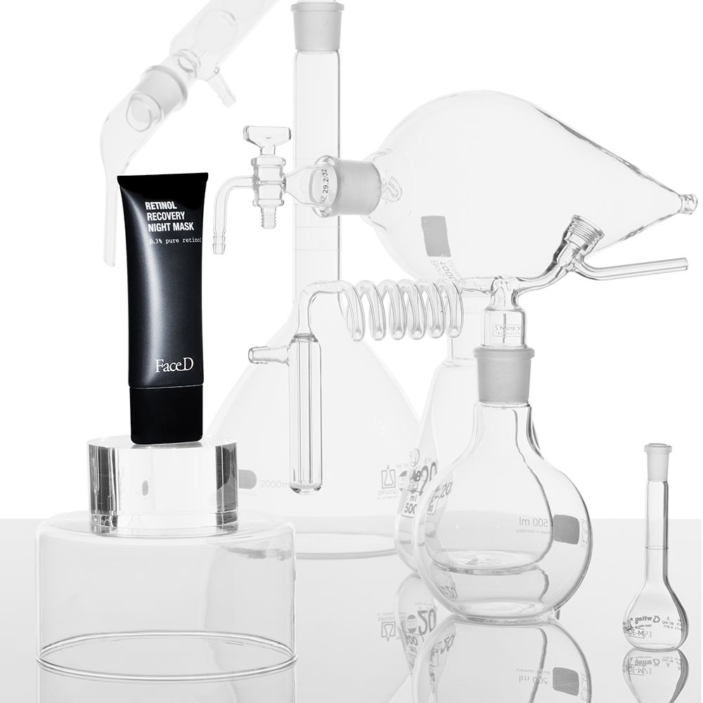 Schwarze Tube auf Podest, umgeben von Glasgeräten. Aufschrift: Retinol Recovery Night Mask, FaceD.