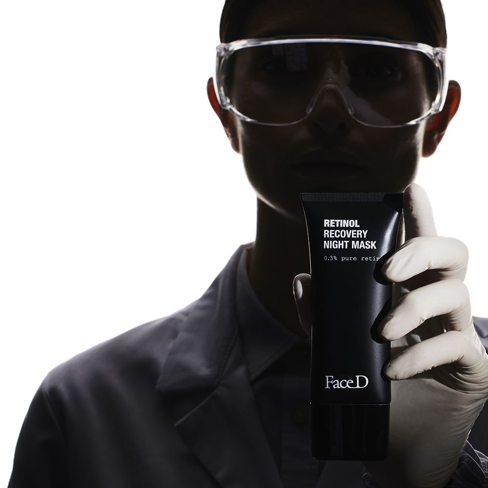 Person hält schwarze Tube. Aufschrift: Retinol Recovery Night Mask, 0.3% pure retinol. Marke: FaceD. Person trägt Schutzbrille.