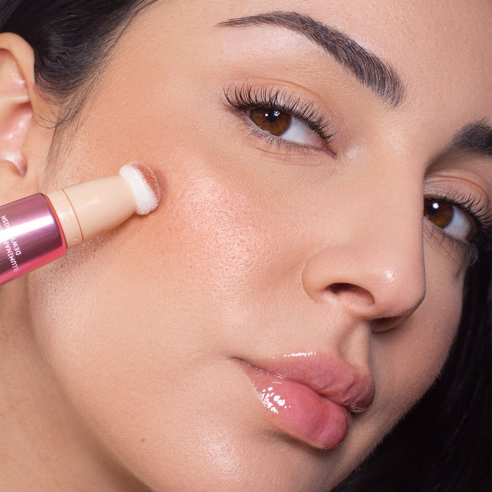 Donna applica ASTRA Make-Up Light Therapy sulla guancia. Applicatore a spugna. Primo piano.